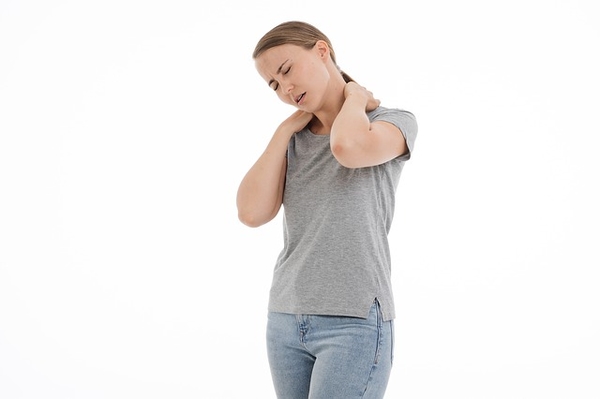 Woman holding neck with hand, experiencing neck pain or discomfort