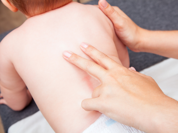 Healthcare provider examining infant's spine and back during chiropractic assessment