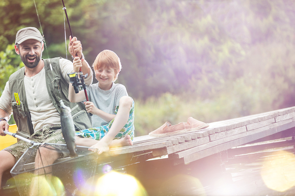 Adult and child holding fishing rods in a boat on water