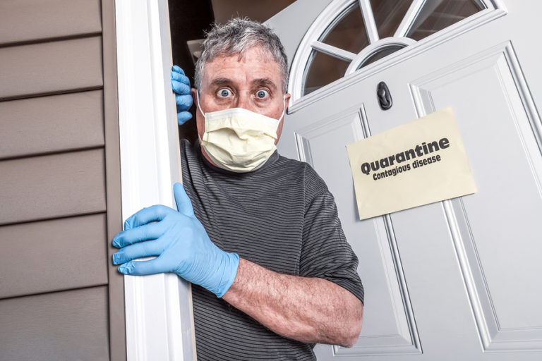 Man wearing protective mask and gloves peering from doorway with quarantine notice affixed to door
