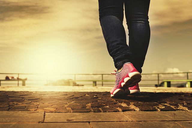 Person wearing pink running shoes and black pants jogging on wooden boardwalk at sunset