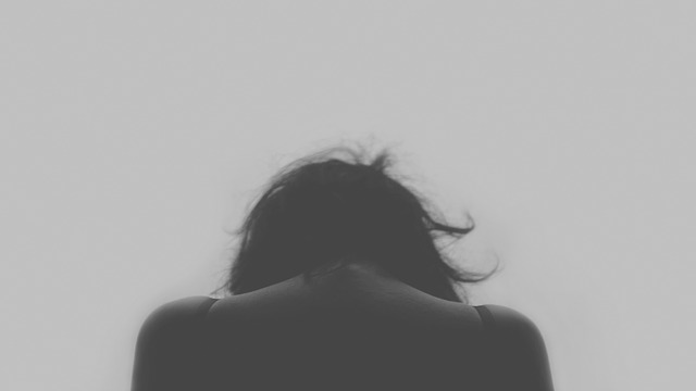 Person viewed from behind with head bowed down, black and white portrait