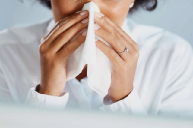 Person holding tissue to nose while coughing or sneezing