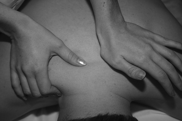 Hands massaging lower back and shoulder area of a person experiencing discomfort