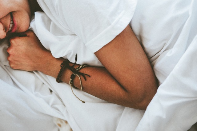 Person wearing white shirt and beaded bracelets with arms crossed over chest