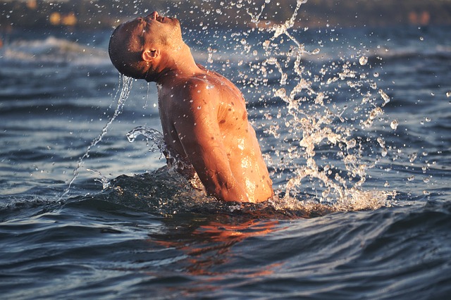 Man splashing in ocean water with waves and sunlight