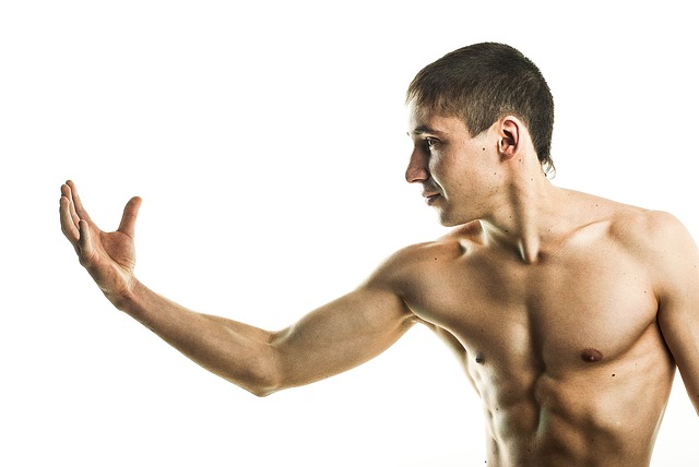 Shirtless man with muscular build extending arm in pushing gesture against white background