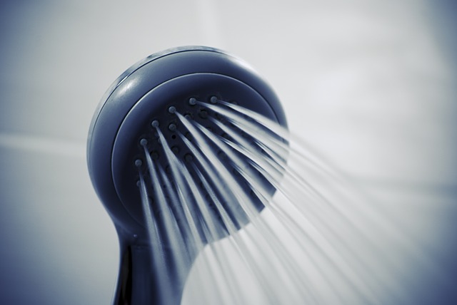 Dark blue showerhead spraying water streams against a light background