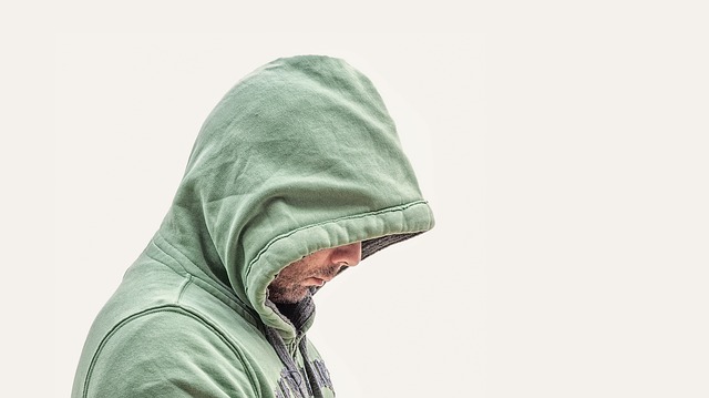 Person wearing green hoodie with hood pulled over head against white background