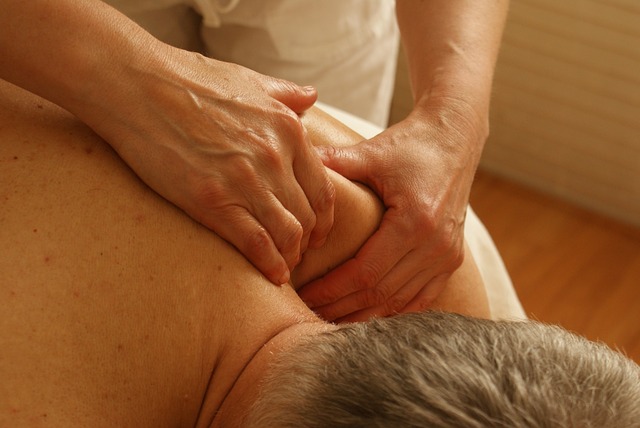 Hands performing therapeutic massage on patient's shoulder and back
