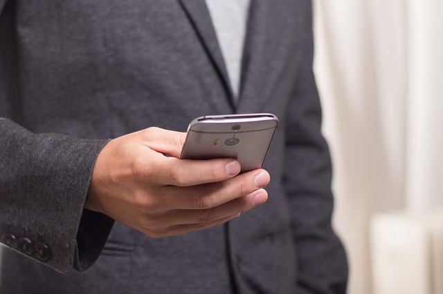 Person in gray blazer holding smartphone in hands