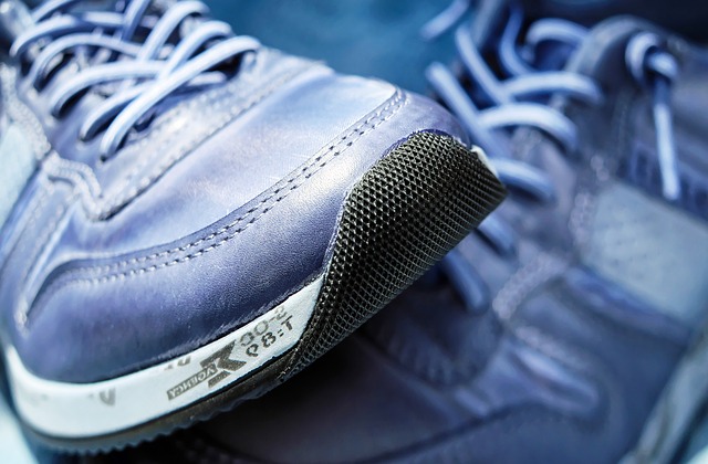 Blue and white athletic shoe with white laces and textured black sole on blue background