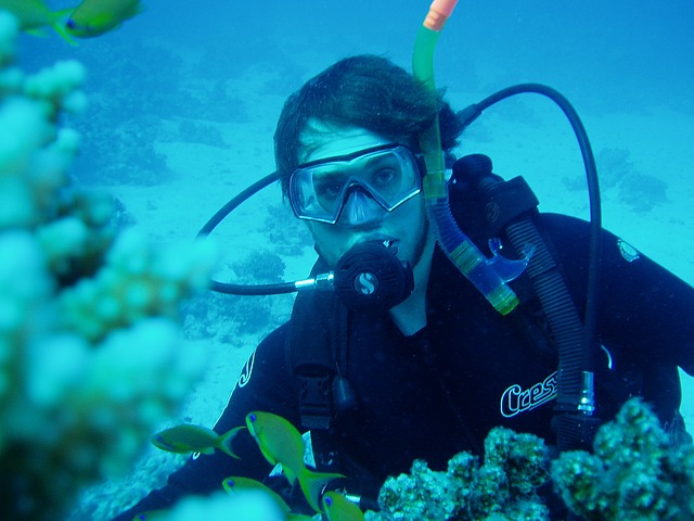 Scuba diver underwater wearing full diving gear surrounded by coral reef